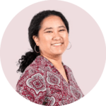 Woman with black hair, circle earrings, red pattern top smiling