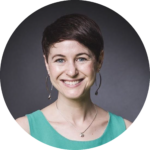 Woman smiling with silver earrings, turquoise dress and short brown hair